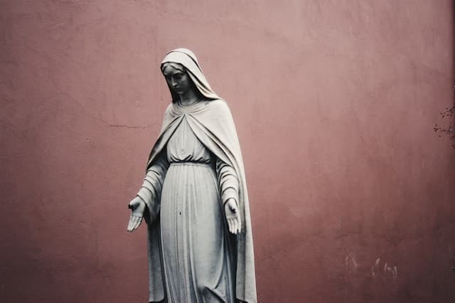 Stone statue of Mary against a rose-colored wall